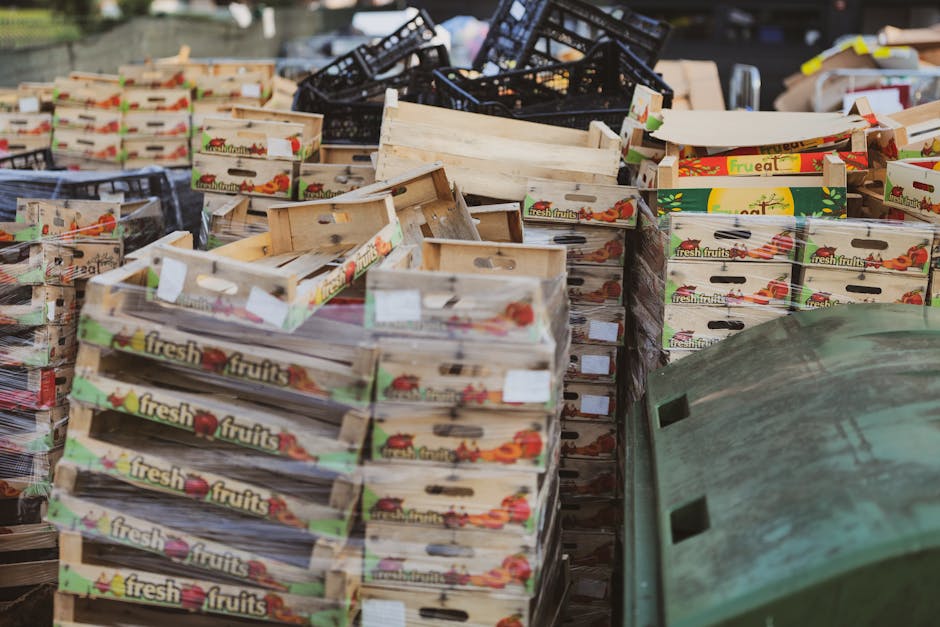 A large collection of emptied wooden fruit boxes, mainly light-colored with printed labels featuring images of various fresh fruits and the words 'fresh fruits' on the sides, stacked and scattered in 